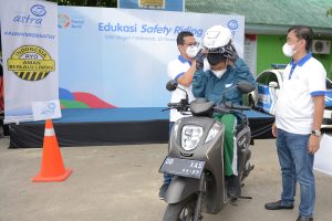 Director Asuransi Astra, Mulia K. B. Siregar dan Adi Sepiarso membantu pemakaian safety kit kepada murid saat edukasi safety riding di SMKN 7 Makassar